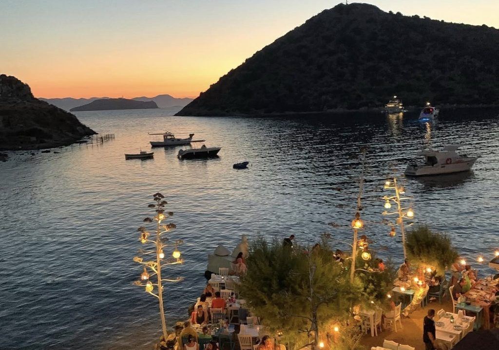 Gümüşlük koyunda gün batımı ve deniz kenarı masalar