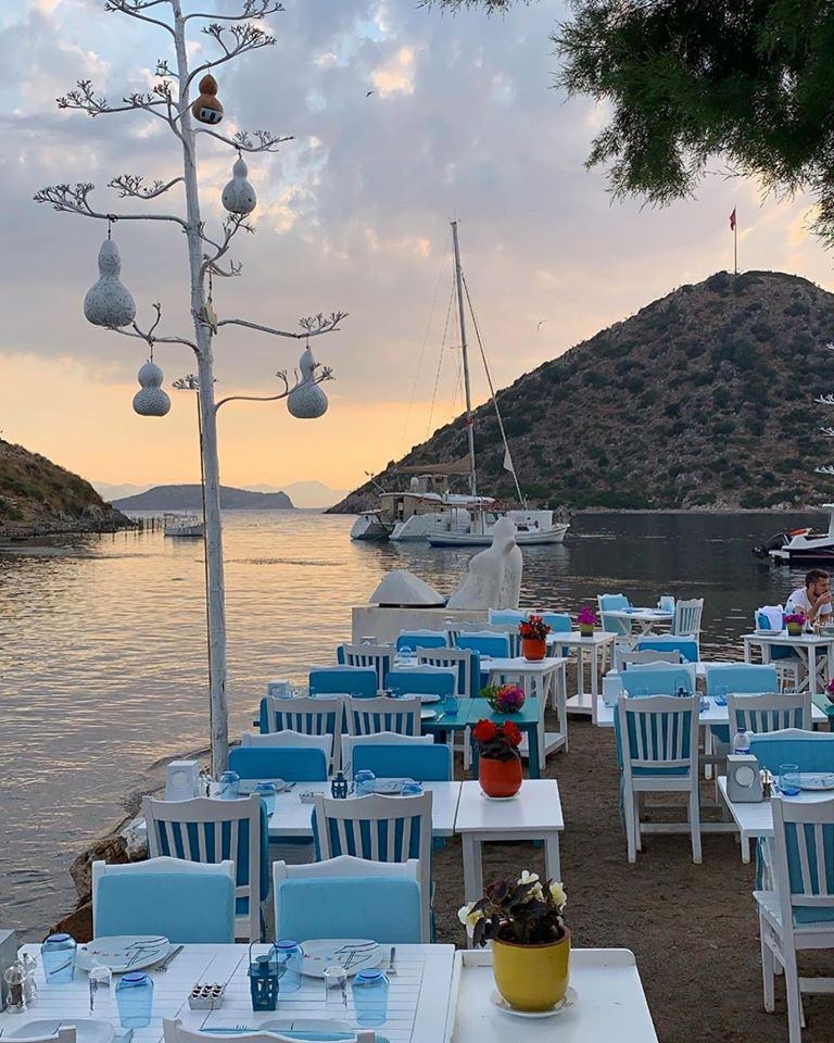 Gün batımında mavi sandalyeli deniz kenarı masalar